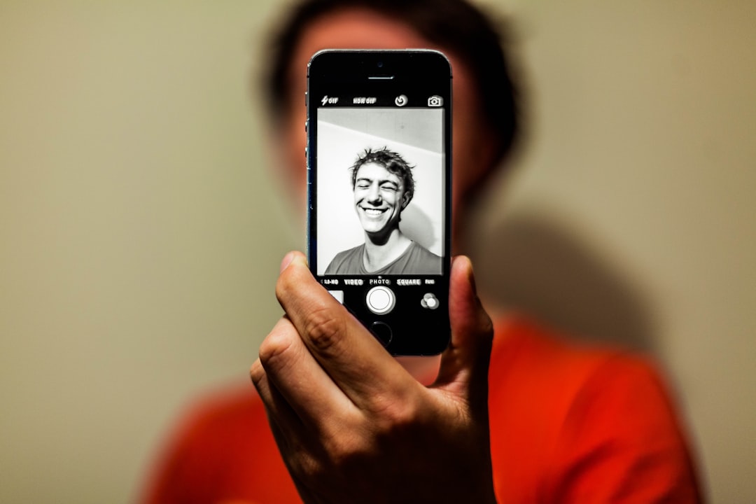 Person taking a selfie with a smartphone, illustrating privacy questions around uploading personal photos to AI services