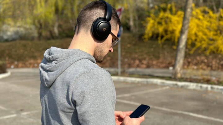 Person using a smartphone with headphones representing Google Translate Live Translate updates on iPhone and Android