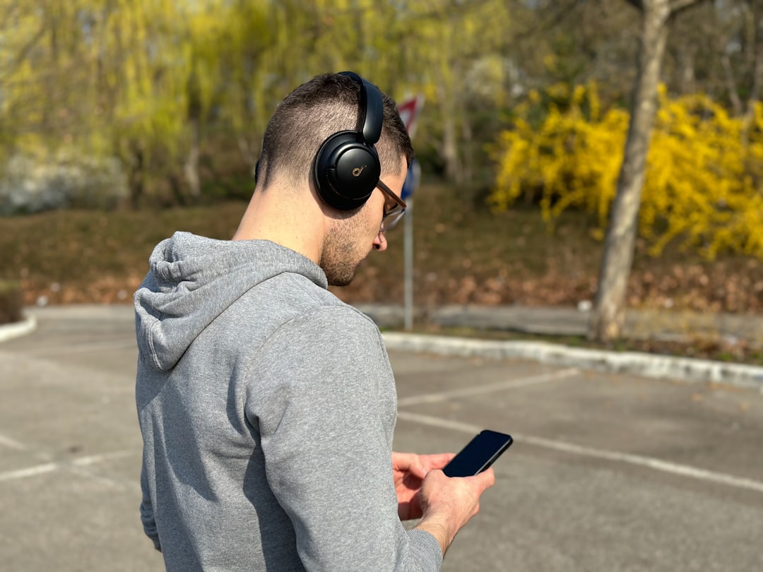 Person using a smartphone with headphones representing Google Translate Live Translate updates on iPhone and Android