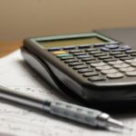 Calculator and pen on a desk illustrating the annual cost of AI subscriptions