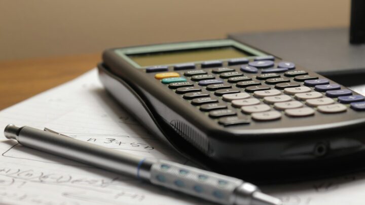 Calculator and pen on a desk illustrating the annual cost of AI subscriptions