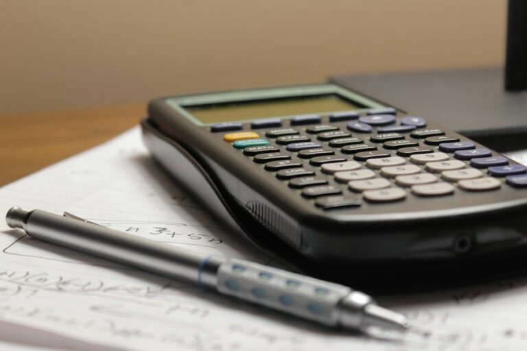 Calculator and pen on a desk illustrating the annual cost of AI subscriptions