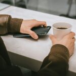 Person holding a coffee mug in an everyday lifestyle setting, illustrating how smartphones fit into daily routines